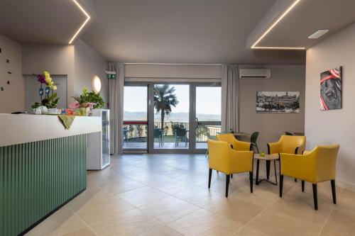 a kitchen and dining room with yellow chairs and a counter at Tuscasì Aparthotel in Sovicille