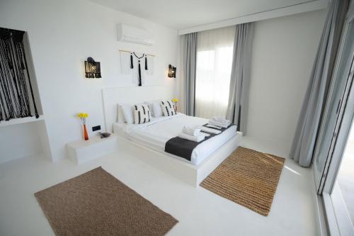 a white bedroom with a bed and a rug at Çamlık 87 Hotel Ayvalık in Ayvalık