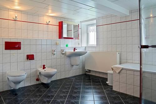 a bathroom with two toilets and a sink and a tub at Auf der Heide Gasthof & Pension in Waltersdorf