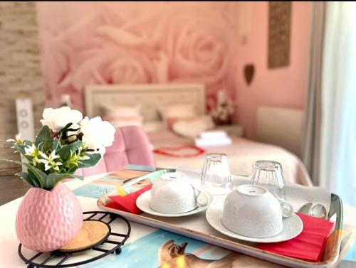 - une table avec des assiettes et des tasses sur un plateau avec un lit dans l'établissement Les nids de la Baie, à Favières