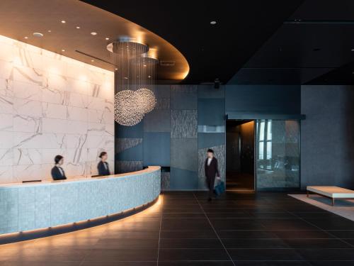 a lobby of a building with people sitting at a counter at Mitsui Garden Hotel Toyosu Premier - Tokyo in Tokyo