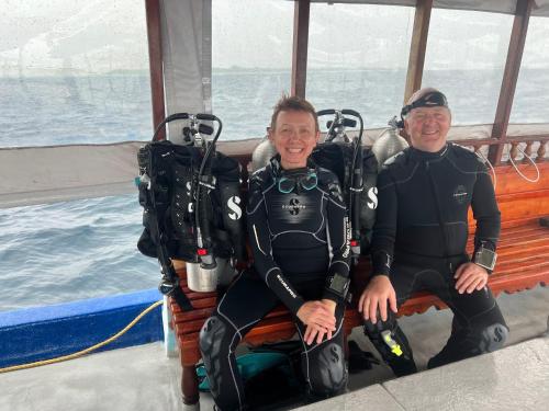two men in wetsuits sitting on a boat at Dive Villa One Ocean in Gemanafushi