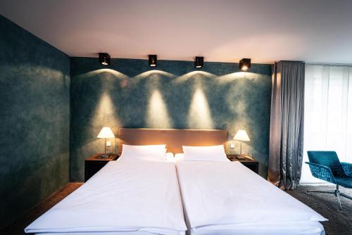 a bedroom with a large white bed and a chair at Hotel Der Blaue Reiter in Karlsruhe