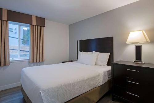 a bedroom with a bed and a lamp and a window at Travelodge by Wyndham Kamloops Mountview in Kamloops