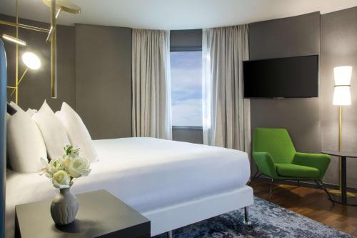 a hotel room with a bed and a green chair at NH Collection Buenos Aires Jousten in Buenos Aires