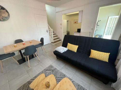 un salon avec un canapé noir et une table dans l'établissement LES PINS - 24 Heures du Mans, au Mans