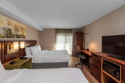 a hotel room with two beds and a flat screen tv at Comfort Inn South in Brossard