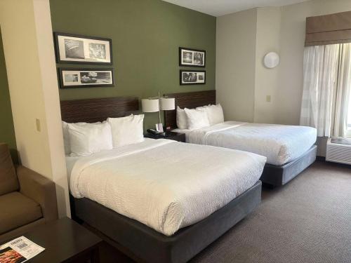 a hotel room with two beds and a chair at Sleep Inn & Suites Queensbury - Lake George in Queensbury