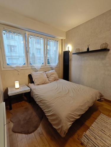 - une chambre avec un lit, une table de chevet et des fenêtres dans l'établissement Studio Paris Montmorency, à Paris