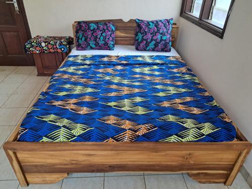 a bed with a blue comforter on it at Au Bel Air in Ouidah
