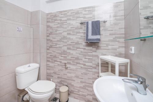 a bathroom with a white toilet and a sink at Silia apartments 3 in Ampavris