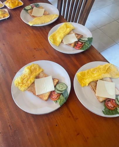 quattro piatti di prodotti per la colazione su un tavolo di legno di Besakih villa a Besakih