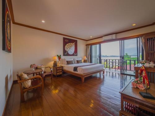 a bedroom with a bed and a table and a balcony at Chiangkhan River Mountain Resort in Chiang Khan