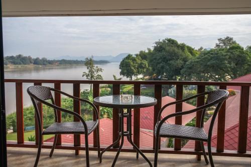 a table and two chairs on a balcony with a view at Chiangkhan River Mountain Resort in Chiang Khan