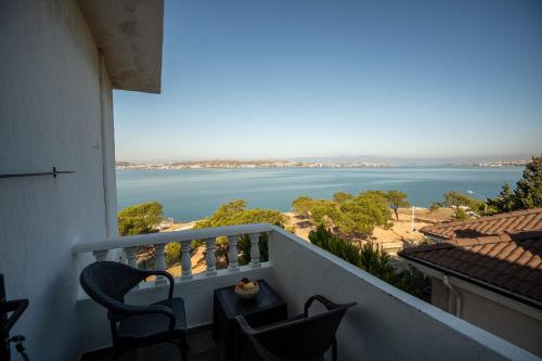 a balcony with chairs and a view of the water at Çamlık 87 Hotel Ayvalık in Ayvalık