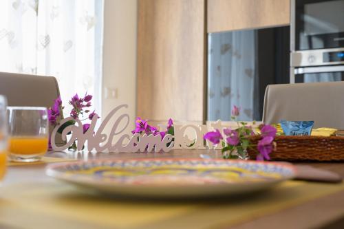 a table with a plate on a table with purple flowers at La MaGia del Tramonto in Salerno