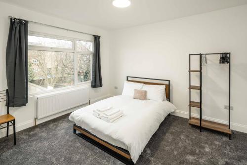 a bedroom with a bed with white sheets and a window at JB Stays Croydon in Thornton Heath