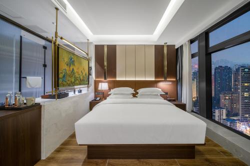 a bedroom with a white bed and a large window at Chongqing Junsheng Yunduan Riverview Hotel in Chongqing