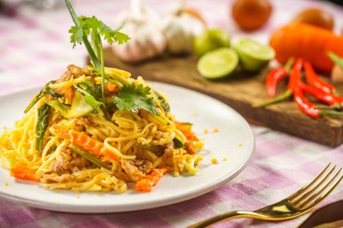 a plate of food with noodles and vegetables on a table at Sabara Angkor Resort & Spa in Siem Reap