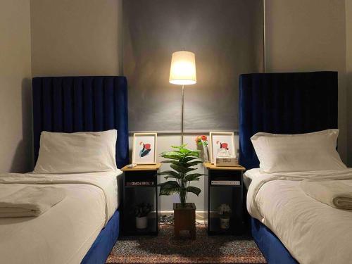 a bedroom with two beds and a lamp and a plant at شقة 7 هادئة بتصميم انيق ثلاث غرف ودخول ذاتي in Al Khobar
