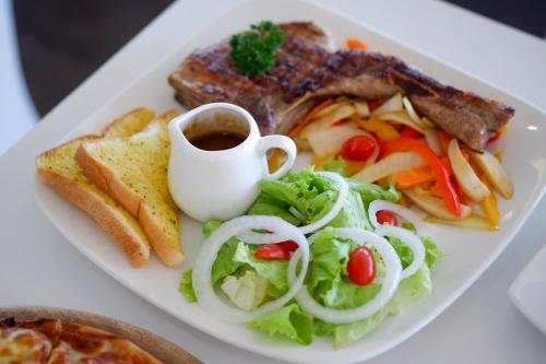 a plate of food with a salad and meat and bread at Chiangkhan River Mountain Resort in Chiang Khan
