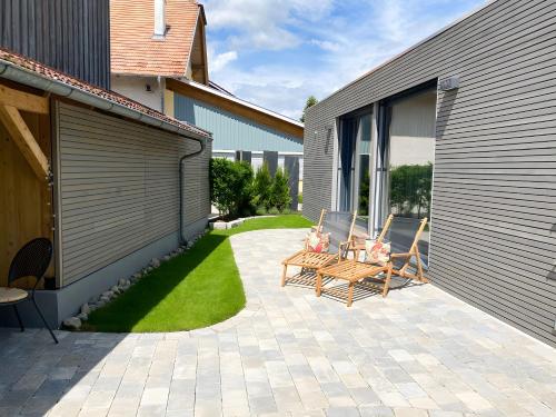 a patio with two chairs and a table next to a building at Beim Dorfbach - Die Hofchalets in Kressbronn am Bodensee