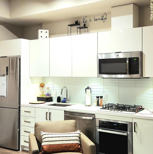 a kitchen with white cabinets and a stove top oven at Luxurious Downtown condo with spectacular views in Calgary