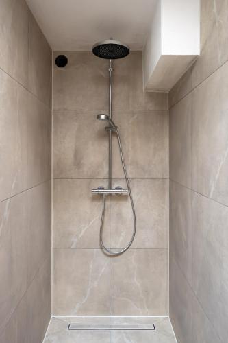 a shower with a shower head in a bathroom at Beautiful Beach Holiday Home with Sauna and Garden in Wijk aan Zee