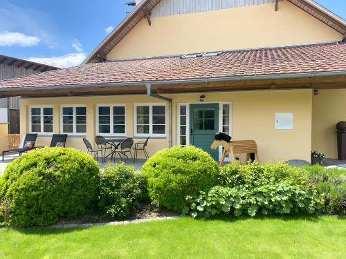 a house with a green door and some bushes at Beim Dorfbach - Die Hofchalets in Kressbronn am Bodensee