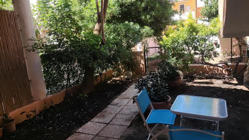 two blue chairs and a table in a garden at Holiday Rooms in Santa Teresa in Santa Teresa Gallura