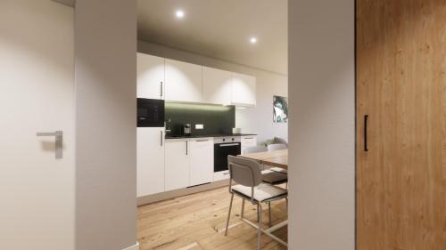 a kitchen with white cabinets and a table with a chair at myQuartier Urban Residences in Innsbruck