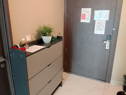 a chest of drawers and a door with a plant on it at Apartemen grand jati junction in Medan