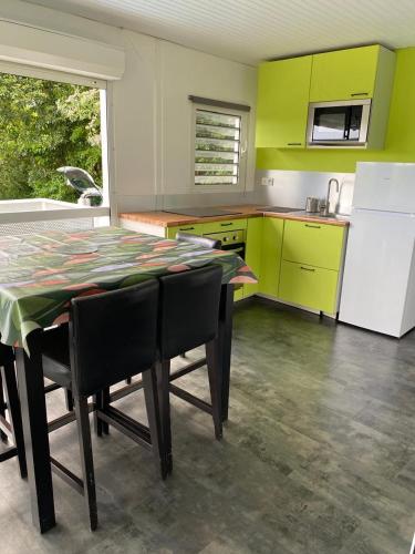 a kitchen with a table with chairs and a refrigerator at Le domaine de Périolat in Le François