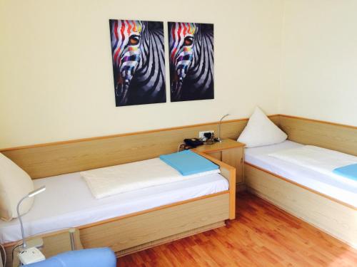 two beds in a room with paintings of zebras at Hotel Garni am Goetheplatz in Bad Münster am Stein-Ebernburg