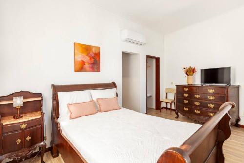 una camera da letto con un letto, una cassettiera e una televisione di Casa da Avó Zilda a Guimarães