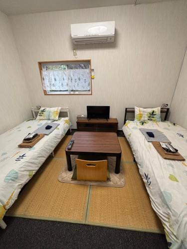a room with two beds and a table between them at Hostel John Mang ゲストハウス ジョン in Tosa