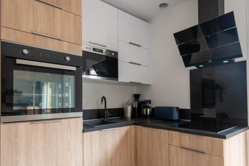 a kitchen with white cabinets and black appliances at Bleu cargo in Biscarrosse