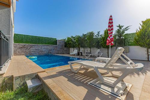 a pool with a lounge chair and an umbrella at Villa Tosun in Belek
