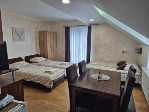 a hotel room with two beds and a table and a television at Apartments Vila Djurdja in Kopaonik