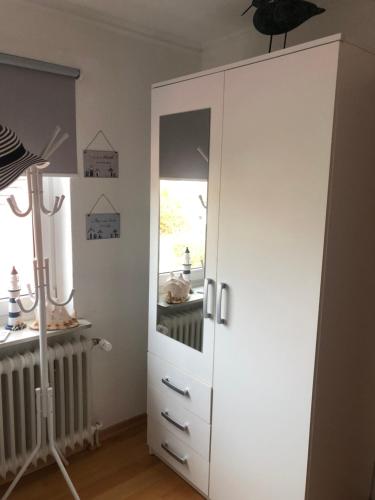 a white cabinet with a mirror in a room at Wattlöwe ruhige Ferienwohnung mit Terrasse nahe Eider & Deich in Tönning