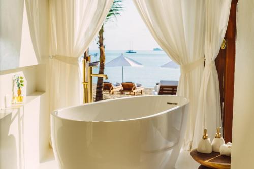 a bath tub in a bathroom with a view of the ocean at Zazen Boutique Resort & Spa in Bophut