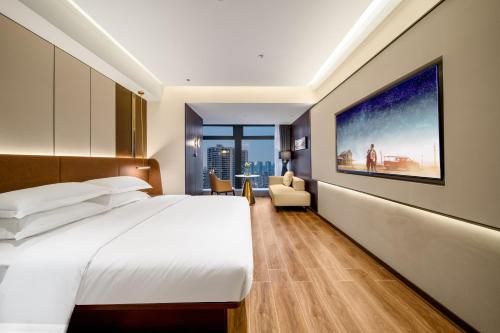 a hotel room with a bed and a large painting on the wall at Chongqing Junsheng Yunduan Riverview Hotel in Chongqing
