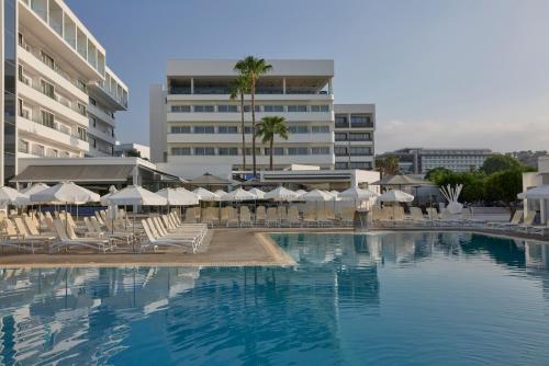 a hotel swimming pool with chairs and umbrellas at Atlantica Sancta Napa Resort in Ayia Napa