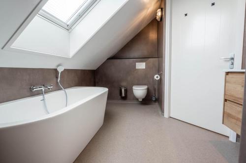 a bathroom with a white tub and a skylight at Appartementen De Witte Brugh in Buren