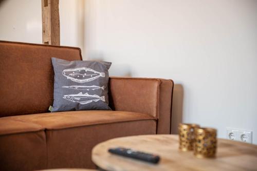 a brown couch with a pillow and a table at Appartementen De Witte Brugh in Buren
