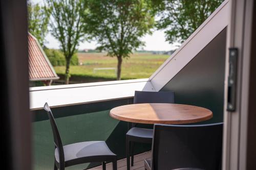 a table and chairs on a balcony with a window at Appartementen De Witte Brugh in Buren