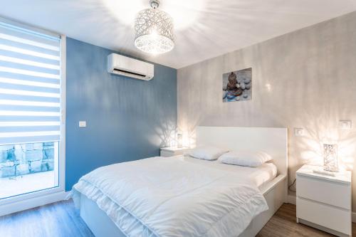 - une chambre avec un lit blanc et un mur bleu dans l'établissement Superbe F2 Spacieux - Saint Raphael, à Saint-Raphaël