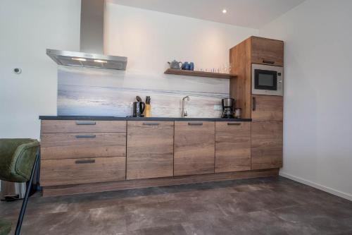 a kitchen with wooden cabinets and a sink at Appartementen De Witte Brugh in Buren