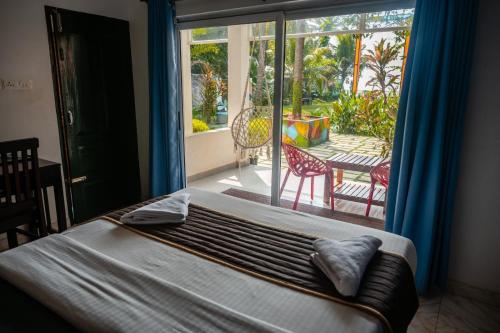 a bedroom with a bed and a large window with a patio at Sky Frame Beach Resort in Varkala