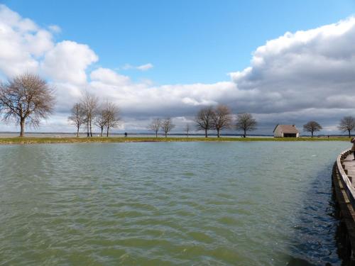 une grande étendue d'eau avec des arbres et un bâtiment dans l'établissement La Maison du Port, à Saint-Valery-sur-Somme